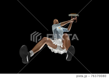 Female professional tennis player in action, motion isolated on black background, look from the bottom. Concept of sport, movement, energy and dynamic. 76370080
