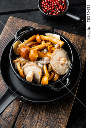 Wild mushrooms Boletus edulis and cap boletus in a jar, on black wooden table background 76370431