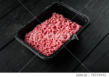 Minced meat in packaging, on black wooden table background Minced meat in packaging, on black wooden table background 76370432