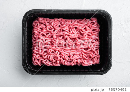 Ground beef meat in plastic tray, on white stone background, top view, flat lay 76370491