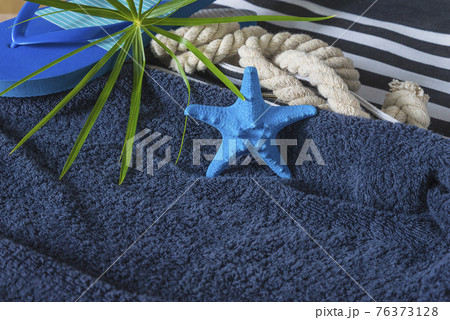 Summer Beach holidays concept. Blue starfish, flip flop and beach bag on dark blue towel. Space for text, selective focus 76373128