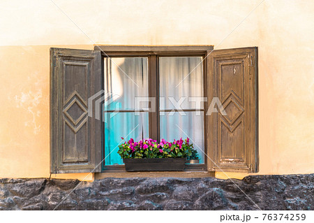 Bavarian or austrian wooden window with red geranium flowers on house in Europa 76374259