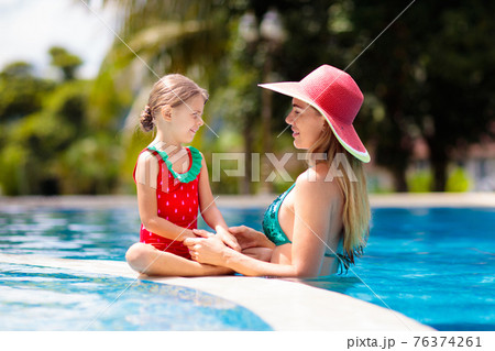 Mother, child at swimming pool. Mom and kid swim. 76374261