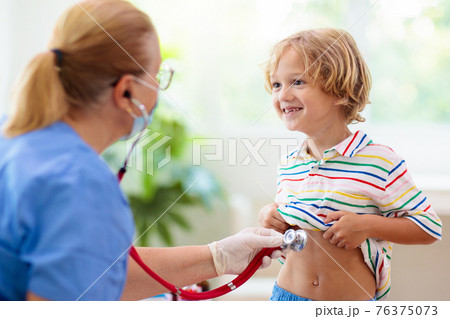 Doctor examining sick child in face mask 76375073