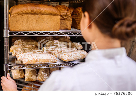Woman looking at rack of freshly baked bread Woman looking at rack of freshly baked bread 76376506