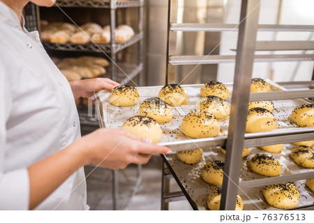 Female hands with baking sheet of buns 76376513