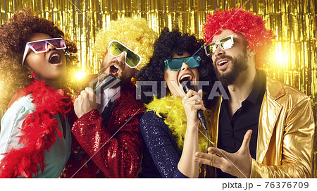 Group of happy people in funny wigs and costumes singing and having fun at karaoke party 76376709
