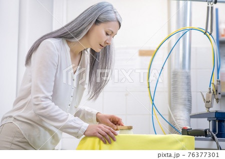 Beautiful adult woman cleaning stain on yellow tshirt Beautiful adult woman cleaning stain on yellow tshirt 76377301