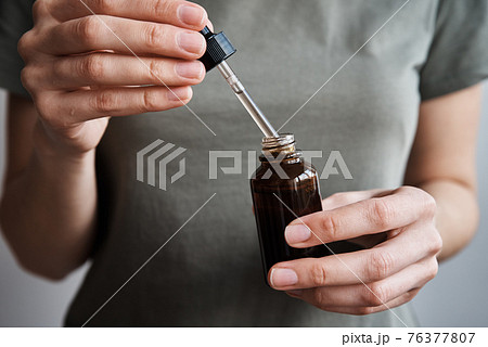 Woman holds bottle with cosmetic serum and essential oil Woman holds bottle with cosmetic serum and essential oil 76377807