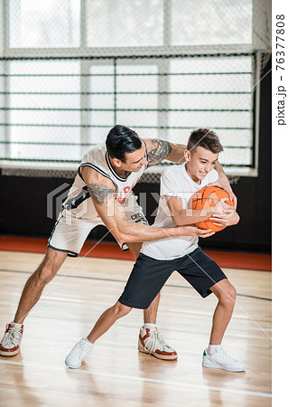 Dark-haired man playing basketball with a boy Dark-haired man playing basketball with a boy 76377808