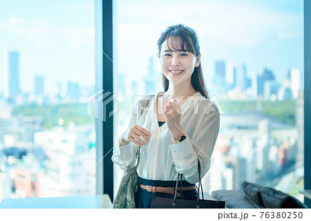 商業ビルの高層階でショッピングバッグを持つ若い女性 76380250