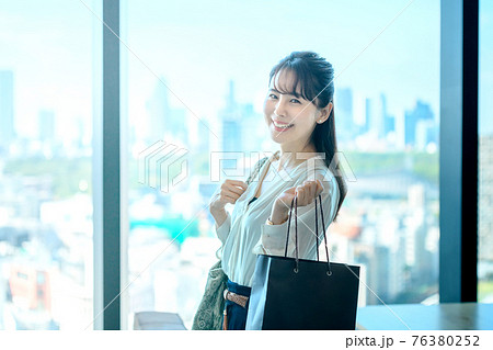商業ビルの高層階でショッピングバッグを持つ若い女性 76380252