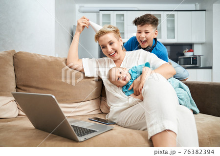Woman with her two sons having video chat on laptop Woman with her two sons having video chat on laptop 76382394