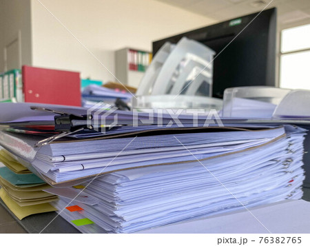 Stack of papers documents in archives files with clip papers on table at offices, Busy offices and Pile of data unfinished folders on office desk indoor near window, Business concept 76382765