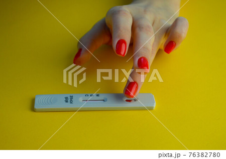 coronavirus test on a yellow, bright background. medical analysis. a girl with a bright red manicure puts her ring finger to perform the procedure 76382780