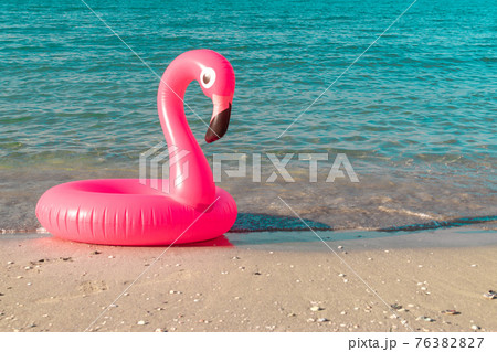 Flamingo print. Pink inflatable flamingo in blue sea water on summer ocean beach background. Minimal summer concept. 76382827