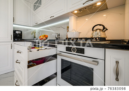 Luxurious white modern kitchen interior, drawers pulled out, dishwasher's door open 76383098
