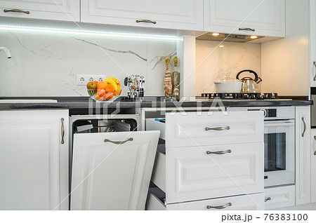 Luxurious white modern kitchen interior, drawers pulled out, dishwasher's door open Luxurious white modern kitchen interior, drawers pulled out, dishwasher's door open 76383100