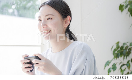 家でゲームをする若い女性 76383313
