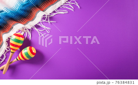 Cinco de Mayo holiday background made from maracas, mexican blanket stripes or poncho serape on purple background. 76384831
