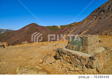 秋の栃木県那須岳の峰の茶屋避難小屋前の道標越しに隠居倉、剣が峰方面を見る 76386448