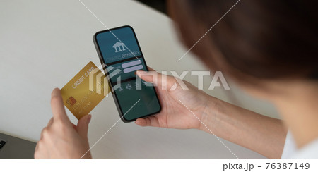 Close up hand of woman making card payment through mobile phone to pay bills 76387149