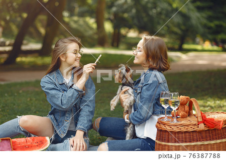 Two cute girls in a park playing with little dog 76387788