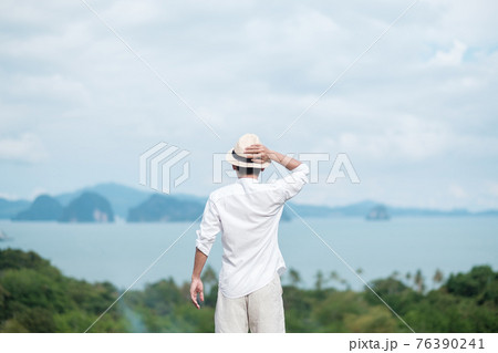 Happy traveler man in white shirt enjoy Beautiful view, alone Tourist with hat standing and relaxing over ocean. travel, summer and vacation concept Happy traveler man in white shirt enjoy Beautiful view, alone Tourist with hat standing and relaxing over ocean. travel, summer and vacation concept 76390241