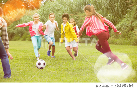 Kids playing football in park 76390564