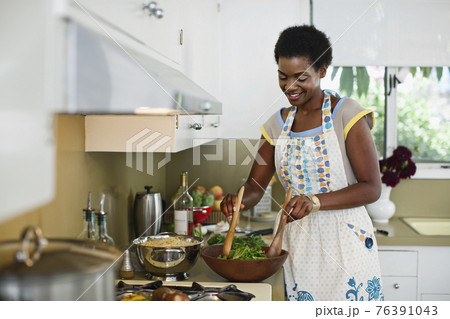 African American woman mixing salad in kitchen African American woman mixing salad in kitchen 76391043