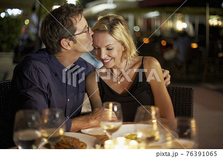 Caucasian husband kissing wife in restaurant 76391065