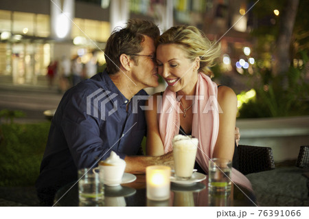 Caucasian man kissing wife in restaurant Caucasian man kissing wife in restaurant 76391066
