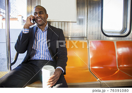 Black businessman talking on cell phone and riding commuter train Black businessman talking on cell phone and riding commuter train 76391080
