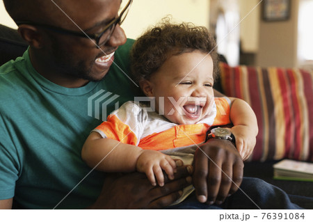 Father and baby laughing on sofa Father and baby laughing on sofa 76391084