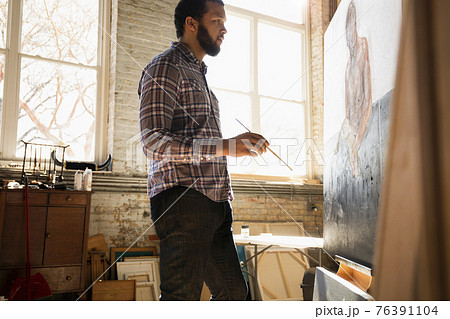 Mixed race artist painting in studio 76391104