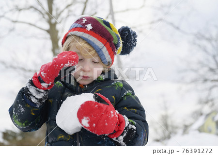 Boy (6-7) holding snowball 76391272
