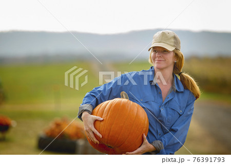 United States, Virginia, Woman harvesting pumpkins 76391793