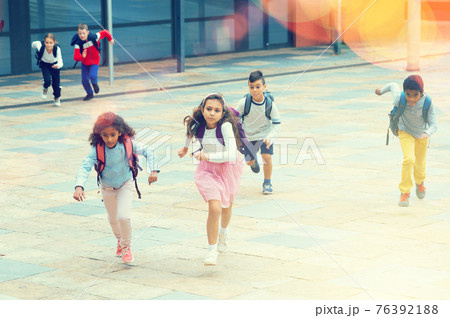 Happy schoolchildren running in the race from school outdoors 76392188