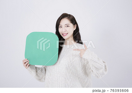 Asian female model with long hair holding copyspace poster, winter beauty promotion concept Asian female model with long hair holding copyspace poster, winter beauty promotion concept 76393606