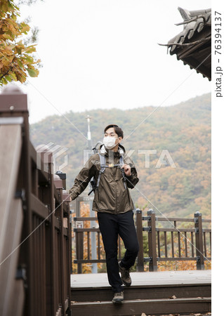 Asian handsome man with mask trekking, climbing autumn mountain 76394137