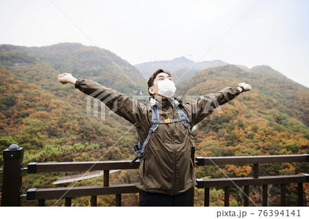 Asian handsome man with mask trekking, climbing autumn mountain Asian handsome man with mask trekking, climbing autumn mountain 76394141