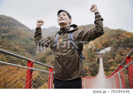 Asian handsome man with mask trekking, climbing autumn mountain 76394240