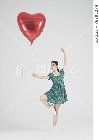 Asian female contemporary dancer making move with heart balloon Asian female contemporary dancer making move with heart balloon 76395274