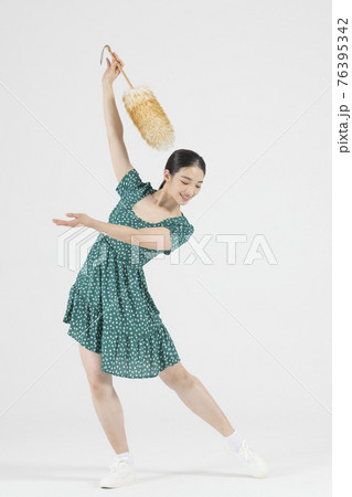 Asian female contemporary dancer holding cleaning tool Asian female contemporary dancer holding cleaning tool 76395342