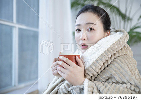 Asian woman drinking hot coffee or tea in blankets 76396197