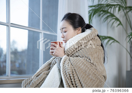 Asian woman drinking hot coffee or tea in blankets 76396366
