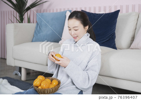 Asian single solo woman living alone concept eating tangerine 76396407