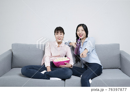 two Asian sisters, women with various facial expressions on sofa eating popcorn watching television two Asian sisters, women with various facial expressions on sofa eating popcorn watching television 76397877
