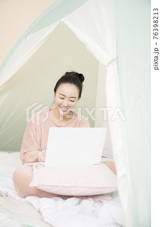 Asian woman in pajams under indoor bed tent Asian woman in pajams under indoor bed tent 76398213