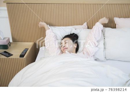 Asian woman waking up and stretching in bed 76398214
